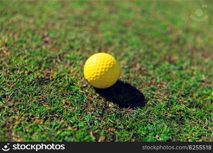 game, entertainment, sport and leisure concept - close up of yellow golf ball on green field grass