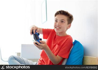 gaming, technology and people concept - smiling boy with gamepad playing video game at home. happy boy with gamepad playing video game at home