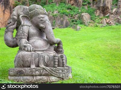 Ganesha statue, made of stone, with a beautiful mountain garden in background
