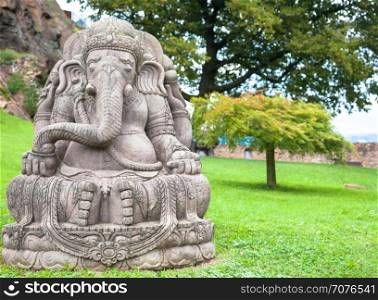 Ganesha statue, made of stone, with a beautiful mountain garden in background