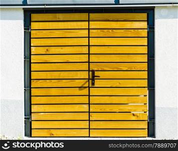 Garage, house or warehouse entry. Yellow wooden door outside.