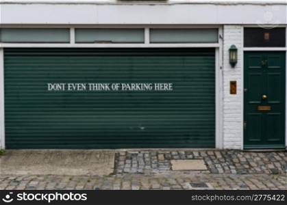 "Garage sign prohibiting parking. Garage sign prohibiting parking painted on the door of a private garage saying "Dont even think of parking here""