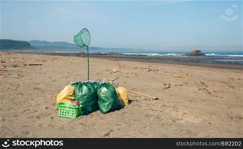 Garbage bags and utensils on the beach after doing a cleaning. Garbage bags and utensils on the beach