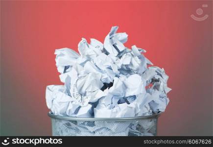 Garbage bin with paper waste against colourful background