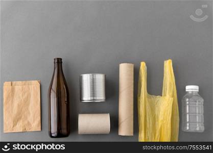 garbage disposal concept - different kind of glass, paper, metallic and plastic household waste on grey background. different kind of household waste