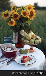 garden and still life. tea party in the garden - a piece of currant pie on a plate, vase with sunflowers and pears on a table with a white tablecloth