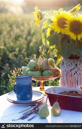 garden and still life. tea party in the garden - currant pie, vase with sunflowers and pears on a table with a white tablecloth
