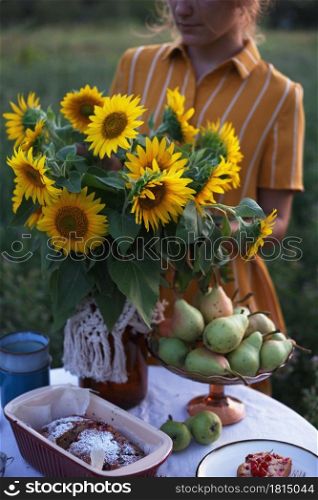 garden and still life. tea party in the garden - girl and bouquet with sunflowers on the table