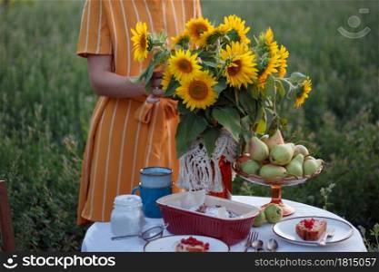 garden and still life. tea party in the garden - girl and bouquet with sunflowers on the table