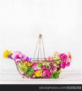 Garden basket with beautiful various colorful garden flowers at white wooden background, front view. Summer gardening concept