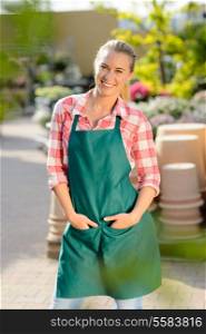 Garden center smiling woman worker posing hands in apron pockets