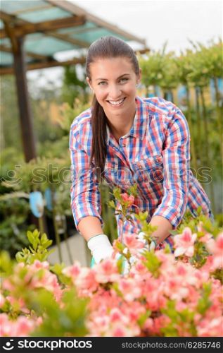 Garden center woman employee working in pink flowerbed smiling