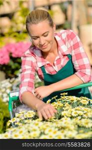 Garden center woman with yellow flowers in shopping cart sunny