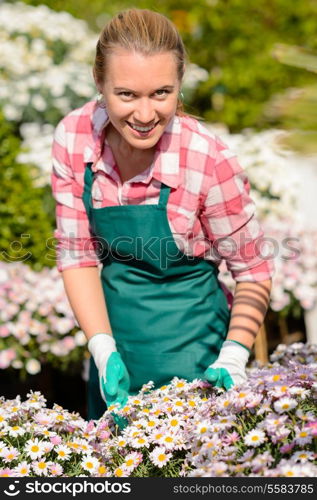 Garden center woman worker in daisy flowerbed smiling sunny