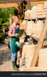 Garden center woman worker make inventory of clay pots sunny