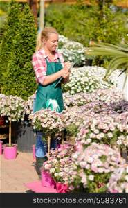 Garden center woman write notes by daisy potted flowers sunny