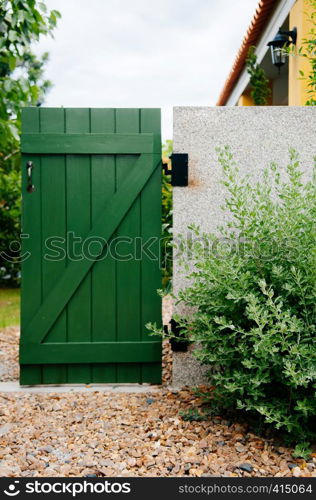 Garden green gate with plant shrub and stone ground. Small country home gardening design