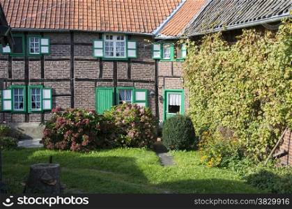 garden in front of old fram house with windows and green shutters