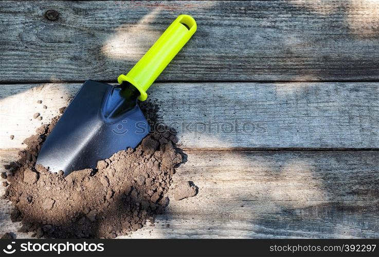 Garden shovel on the milled ground on a wooden background. Garden shovel on the milled ground