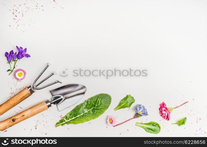 Garden tools and parts of plants and flowers on light background, top view, place for text, border