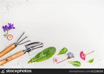 Garden tools and parts of plants and flowers on light background, top view, place for text, border