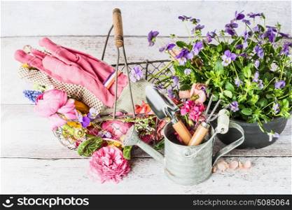 Garden tools with watering can, basket and flowers on gardening table