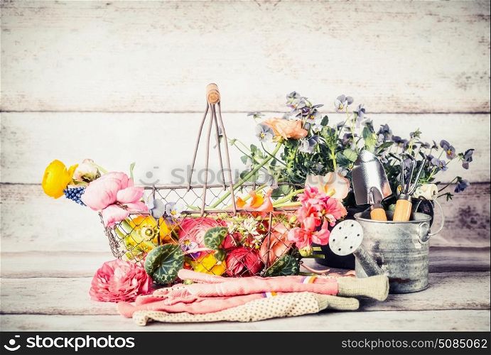 Garden tools with watering can, basket and flowers on gardening table at wooden background, front view