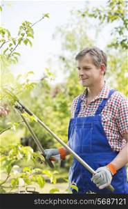 Gardener clipping tree branches at plant nursery