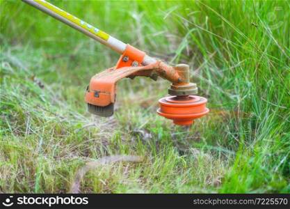 Gardener mowing grass by brush cutter in garden close up . . Gardener mowing grass by brush cutter in garden close up