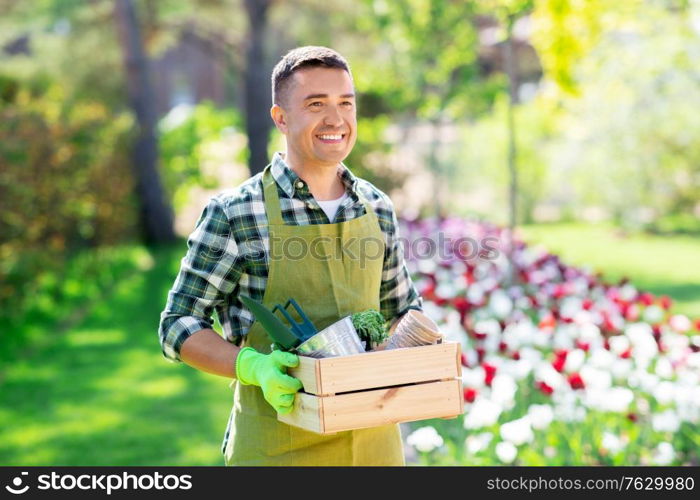 gardening and people concept - happy smiling middle-aged man in apron with tools in box at summer garden. happy man with tools in box at summer garden