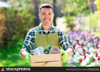 gardening and people concept - happy smiling middle-aged man in apron with tools in box at summer garden. happy man with tools in box at summer garden