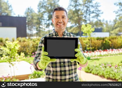 gardening and people concept - happy smiling middle-aged man showing tablet pc computer at summer garden. happy middle-aged man showing tablet pc at garden
