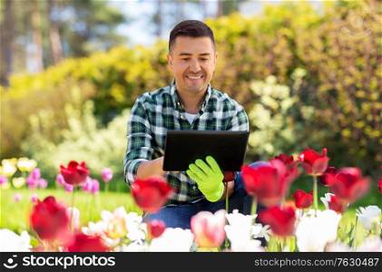 gardening and people concept - happy smiling middle-aged man with tablet pc computer and flowers at summer garden. man with tablet pc and flowers at summer garden
