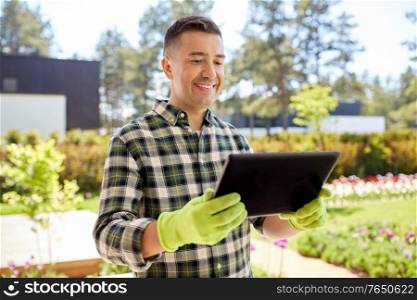 gardening and people concept - happy smiling middle-aged man with tablet pc computer at summer garden. man with tablet pc at summer garden
