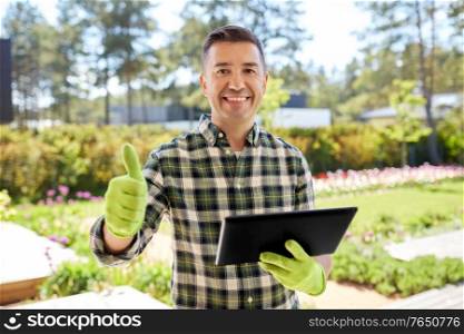 gardening and people concept - happy smiling middle-aged man with tablet pc computer showing thumbs up at summer garden. man with tablet pc showing thumbs up at garden