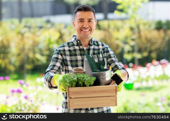 gardening and people concept - happy smiling middle-aged man with tools in box at summer garden. happy man with tools in box at summer garden