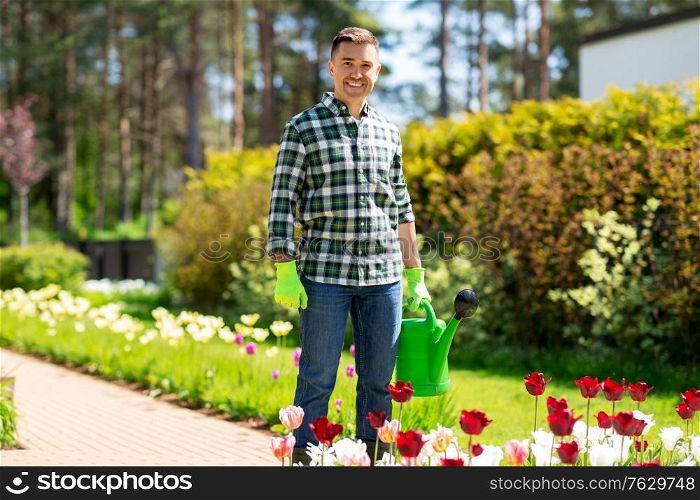 gardening and people concept - happy smiling middle-aged man with watering can and flowers at garden. happy man with watering can and flowers at garden