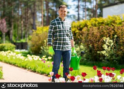 gardening and people concept - happy smiling middle-aged man with watering can and flowers at garden. happy man with watering can and flowers at garden