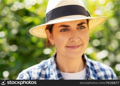 gardening and people concept - portrait of happy smiling young woman in straw hat at summer garden. portrait of woman in straw hat at summer garden