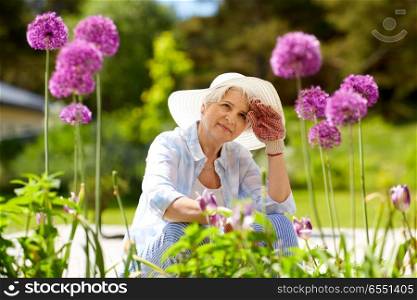 gardening and people concept - tired senior woman or gardener with flowers working at summer garden. tired senior woman with flowers at working garden. tired senior woman with flowers at working garden