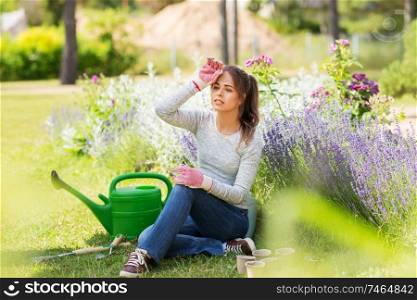 gardening and people concept - tired young woman with garden tools in summer. tired young woman with garden tools in summer