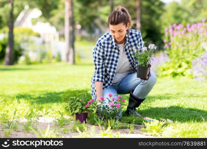 gardening and people concept - woman planting rose flowers at summer garden. woman planting rose flowers at summer garden