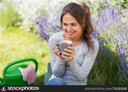 gardening and people concept - young woman drinking tea at summer garden. young woman drinking tea at summer garden