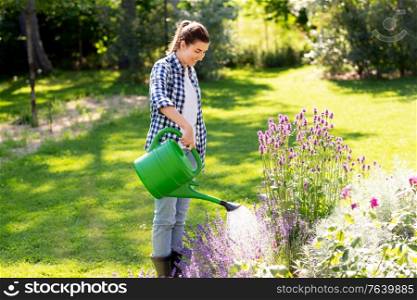 gardening and people concept - young woman with watering can pouring water to flowers at garden. young woman watering flowers at garden