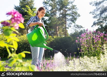 gardening and people concept - young woman with watering can pouring water to flowers at garden. young woman watering flowers at garden