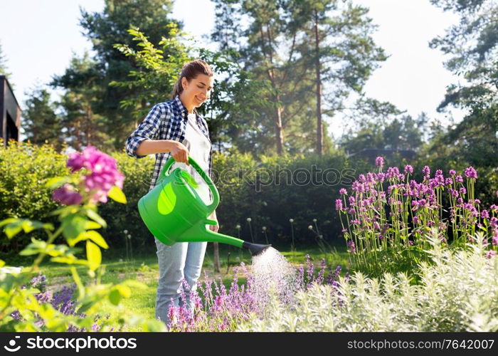 gardening and people concept - young woman with watering can pouring water to flowers at garden. young woman watering flowers at garden