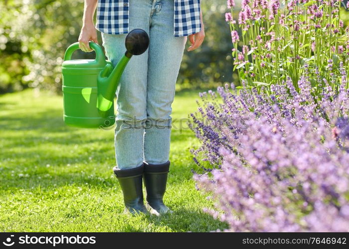 gardening and people concept - young woman with watering can pouring water to flowers at garden. young woman watering flowers at garden