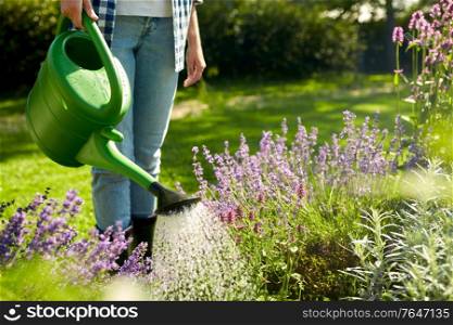 gardening and people concept - young woman with watering can pouring water to flowers at garden. young woman watering flowers at garden