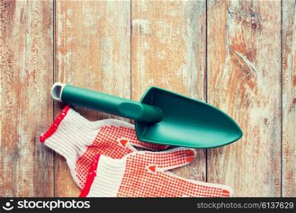 gardening and planting concept - close up of trowel and garden gloves on table. close up of trowel and garden gloves