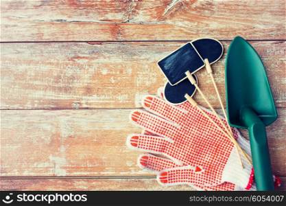 gardening and planting concept - close up of trowel, nameplates and garden gloves on table